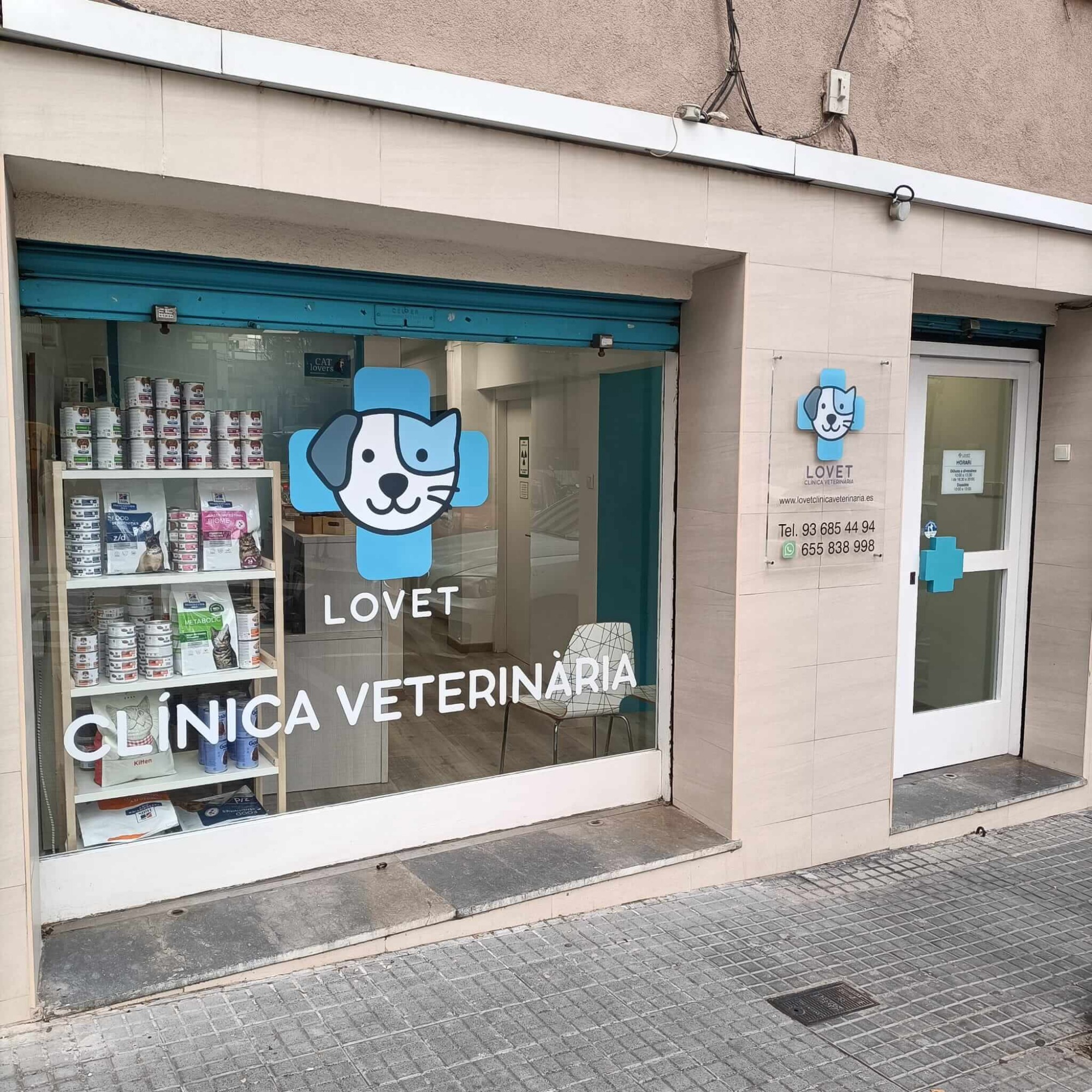Tu clinica veterinaria de confianza en sant feliu de llobregat Fachada de una clínica veterinaria con un perro dibujado y estantes de productos para mascotas.