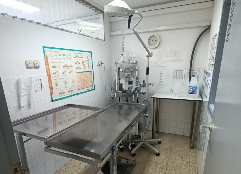 Sala de quirófano con mesa metálica y equipo médico.